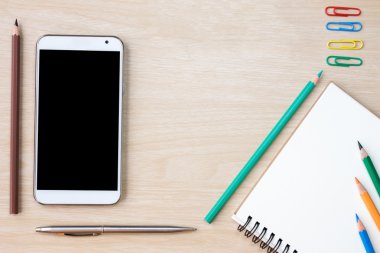 top view of smartphone, notebook and pen, wooden desk with pencil and notepad, on a white background