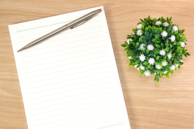 notebook with a pen and a flower on a wooden background
