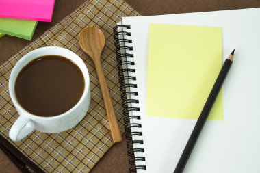 Tahta arka planda bir fincan kahve ve defter.