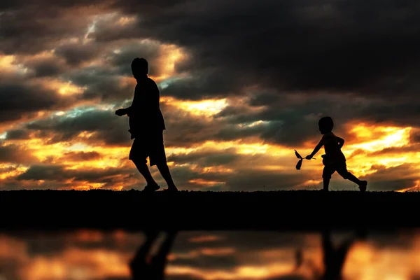 Baba ve oğul siluetleri ile oynamak. — Stok fotoğraf