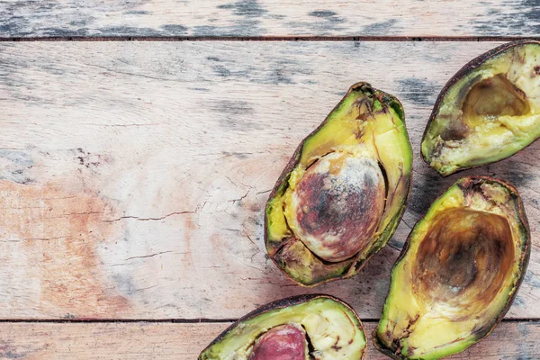 El aguacate está podrido en el suelo de madera . — Foto de Stock