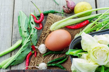 Yumurta ve ahşap zemin üzerinde yemek pişirmek için sebze.