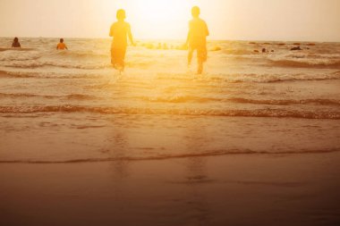 Çocuk gün batımında sahilde.