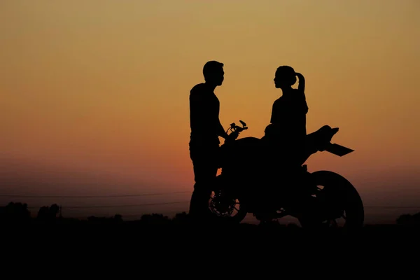 Pary z motocyklem o zachodzie słońca. — Zdjęcie stockowe