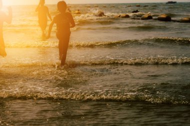 Çocuklar gün batımında koşuyorlar..