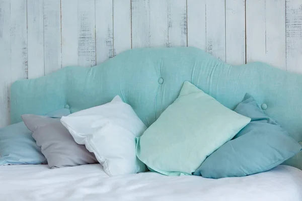 Montones de almohadas en tonos azules, dispuestos en una cama, en una ba de madera — Foto de Stock