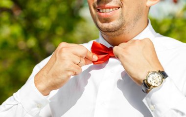 Damat neşeyle bir kırmızı kelebek düzeltir. yakın çekim