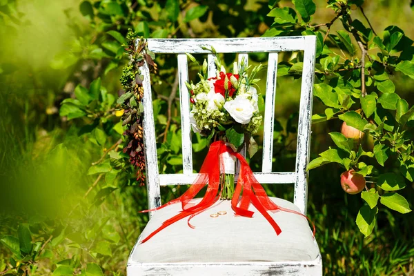 Mooie rode bruids boeket staat op een stoel in het park — Stockfoto