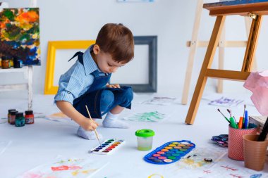 Sevimli, mutlu, beyaz oğlan mavi tişört ve kot boyalar ile berabere