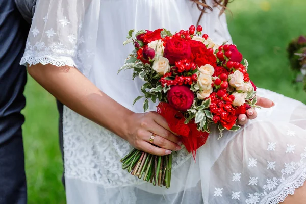 Sposa in abito bianco tenuta in mano delicata, costosa, trendy bouquet da sposa di fiori in marsala e colori rossi. Avvicinamento, vista dall'alto — Foto Stock
