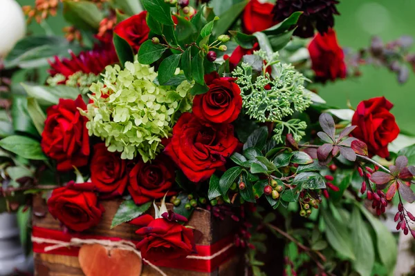 Декор свадебного стола: композиция цветов с розами, ягодами, травами и зеленью, стоящими в деревянной коробке. Детали и украшения невесты, романтический ужин в лесу — стоковое фото