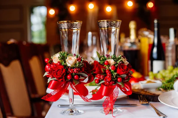 Dos vasos de boda vacíos, decorados con vegetación, rosas rojas y cinta, de pie sobre la mesa del banquete . — Foto de Stock