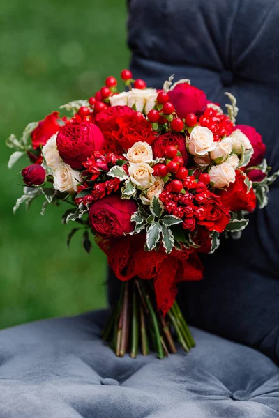 Дорогостоящий, модный свадебный букет из роз в марсале и красных цветов, стоящих на стуле. Декор невесты с цветами — стоковое фото