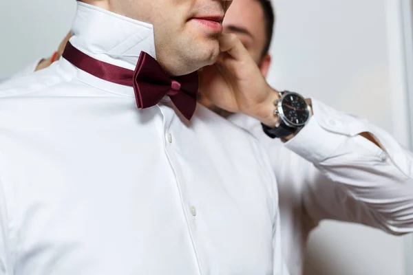 Jeune marié tenant dans ses mains un nœud papillon à pois rouges. Gros plan sur les accessoires de mariage pour hommes . — Photo