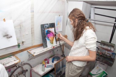 Kız genç parlak renkli resimler bir okulöncesi Studio - Rusya, Moskova - 24 Ocak 2016 Pistole ile boyar