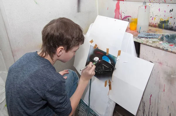 Niño adolescente pinta con un aerógrafo imágenes de colores brillantes en un estudio artístico - Rusia, Moscú - 24 de enero de 2016 —  Fotos de Stock