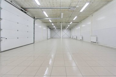 empty parking garage, warehouse interior with large white gates and gray tile floor clipart