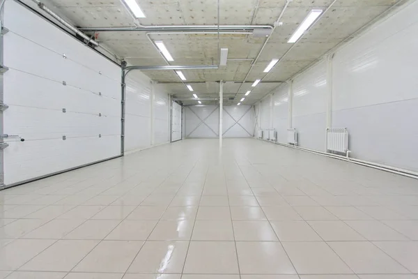 empty parking garage, warehouse interior with large white gates and gray tile floor