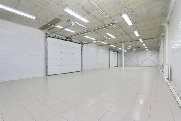 empty parking garage, warehouse interior with large white gates and gray tile floor