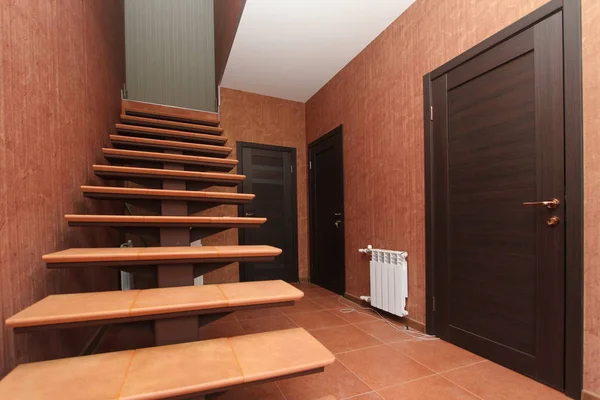 Escalera abierta con escalones de piedra que suben al pasillo interior habitaciones primer plano sobre un fondo de paredes brillantes y puertas oscuras — Foto de Stock
