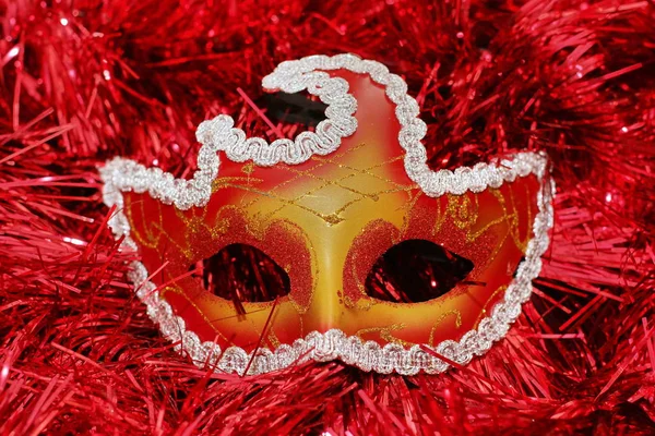 Masque de couleur vive sur un fond rouge Noël arbre tinsel — Photo