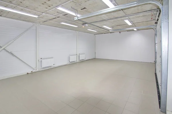Garaje de estacionamiento vacío, interior del almacén con grandes puertas blancas y piso de baldosas grises — Foto de Stock