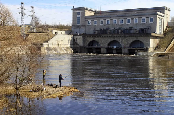 Lidé jsou rybolov na řeky Narva na pozadí vodní elektrárna — Stock fotografie