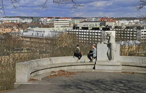 Duas meninas estão sentadas na estátua contra o fundo da paisagem urbana — Fotografia de Stock