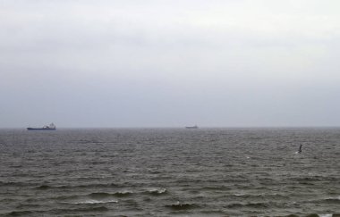 iki gemi, uçurtma sörfçü ve denizin dalgaları ile gri gökyüzü