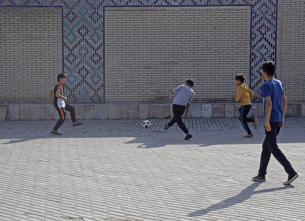 Crianças nativas locais jogando futebol em Samarcanda, Uzbequistão Imagens Royalty-Free