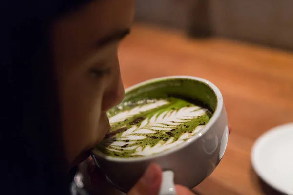 A girl is sipping the hot latte coffee — Stock Photo, Image