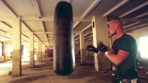 Un atleta fuerte golpea un saco de boxeo. Tiro medio . — Vídeo de stock