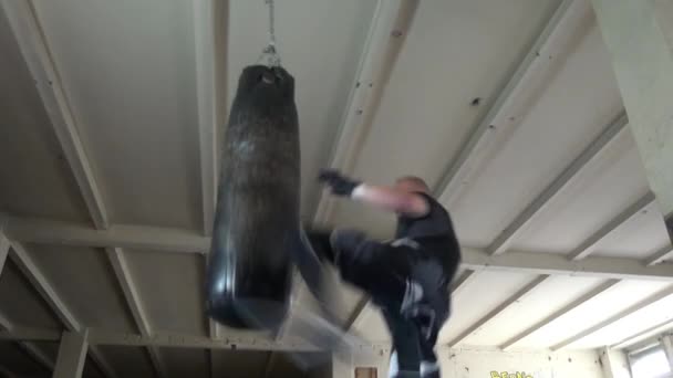 Hombre atleta boxeador saco de boxeo con iluminación de borde dramático en un estudio oscuro — Vídeos de Stock