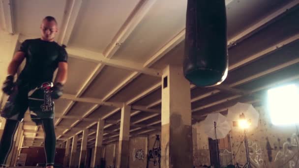 Hombre atleta boxeador saco de boxeo con iluminación de borde dramático en un estudio oscuro — Vídeo de stock