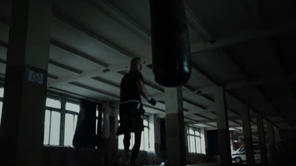 Worek treningowy mężczyzna sportowiec bokser z dramatyczne kanciasty oświetlenia w ciemnych studio — Wideo stockowe