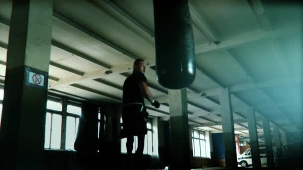 극적인 초 초 조명 어두운 스튜디오에서 남성 선수 복 서 펀치 백 — 비디오