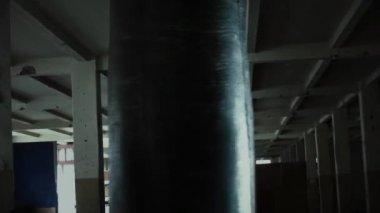 Erkek atlet boxer kum torbası karanlık bir stüdyoda dramatik sinirli aydınlatma ile