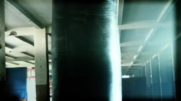 Hombre atleta boxeador saco de boxeo con iluminación de borde dramático en un estudio oscuro — Vídeo de stock