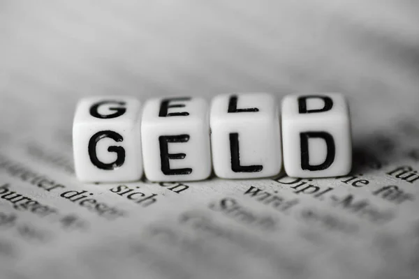 German Word GELD formed by wood alphabet blocks on newspaper — Stock Photo, Image