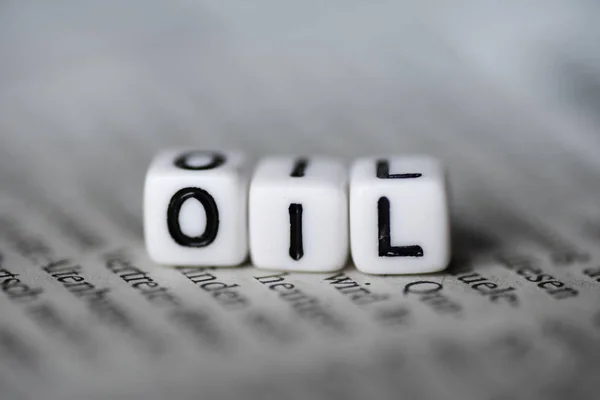 Word OIL formed by wood alphabet blocks on newspaper — Stock Photo, Image