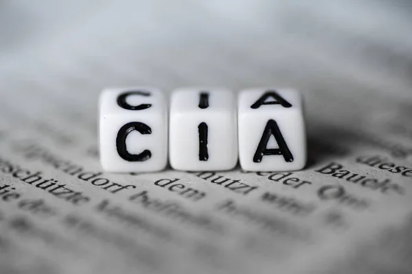 Palabra CIA formada por bloques de alfabeto de madera en el periódico — Foto de Stock