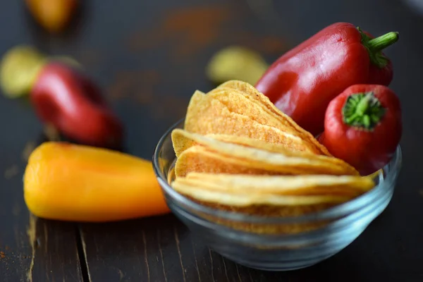 Potatischips med paprika på mörk trä bakgrund — Stockfoto