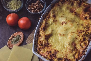 Lazanya hizmet taze domates ile ahşap bir tahta üzerinde katmanlı