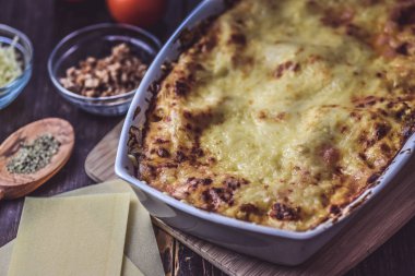 Lazanya hizmet taze domates ile ahşap bir tahta üzerinde katmanlı