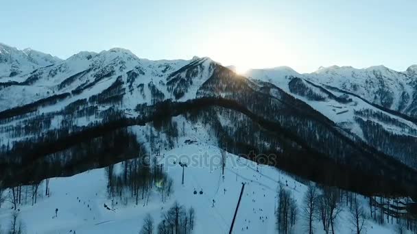 De luchtfoto's. Winter. Rusland. Sotsji 2017. Krasnaja Poljana. Aibga berg. De zon achter de bergen. Kabelbaan voor skiërs. — Stockvideo