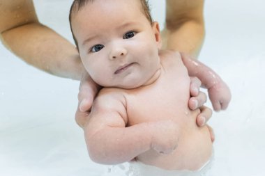 Küçük bir çocuk, annesinin kollarında havuzda bir bebek. Yüzme öğreniyorum. Temiz su. Emzirme