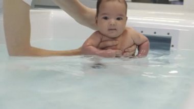 Bebek masanın üzerinde uzanıp kollarına ve bacaklarına masaj yapıyor. Küçük bebek parmakları. Sağlıklı bir yaşam tarzı. Atletizm. Masada yatan çocuk.