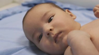 Bebek masanın üzerinde uzanıp kollarına ve bacaklarına masaj yapıyor. Küçük bebek parmakları. Sağlıklı bir yaşam tarzı. Atletizm. Masada yatan çocuk.