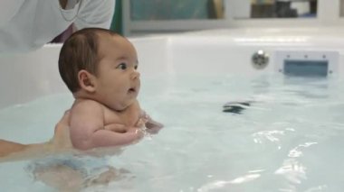 Bebek masanın üzerinde uzanıp kollarına ve bacaklarına masaj yapıyor. Küçük bebek parmakları. Sağlıklı bir yaşam tarzı. Atletizm. Masada yatan çocuk.