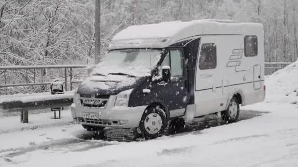 Een camper op de weg. Het sneeuwt. Rv. Een busje. Het is een koude tijd van het jaar. Geen mensen. Rust in de natuur. — Stockvideo